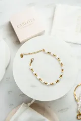 Pulsera dorada con perlas de agua dulce naturales y piezas cilíndricas de acero quirúrgico con baño de oro de 18k.
