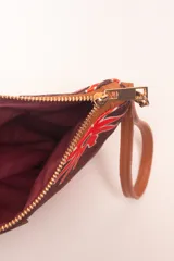 Sobre de algodón a rayas verticales de colores naranja, rosa, marrón, rojo y blanco. Tiene cierre superior con cremallera y tira de cuero marrón para la muñeca.