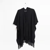 Ruana negra de tejido de punto calado con flecos en el borde inferior.