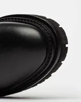 Bota de cuero negro de caña media con diseño liso y suela gruesa.