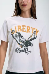 Remera color crudo de corte recto con estampado de un águila y la palabra 'Liberty' en color amarillo.