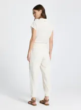 Pantalón jogger color crudo con estampado a cuadros, cintura con cordón ajustable, ribete elástico y minivolantes, bolsillos delanteros, detalles plisados y bajo con botones laterales.