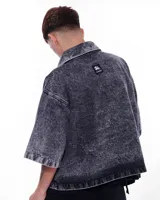 Camisa de denim negra con efecto lavado, corte recto, mangas cortas y bolsillo en el pecho.