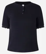 Blusa negra de rib con cuello redondo, manga corta con detalle de retilínea contrastante blanca en el bajo y cierre frontal con botones.