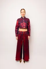 Pantalón jean largo tornasolado en tonos de bordo, rojo y azul. Diseño de pierna oversize con botones laterales que permiten usarlo abierto o cerrado.