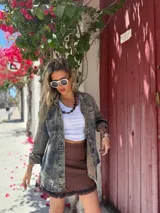 Camisa de denim con lavado ácido (acid wash) en tonos grises y azules, de corte holgado y botones dorados.