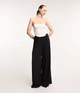 Blusa tipo corset color crema, sin breteles, confeccionada en crepé con bajo asimétrico alargado.