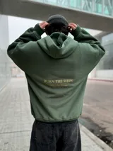 Hoodie verde militar de felpa con frisa gruesa, corte boxy, estampado dorado en la espalda con la frase "BURN THE SHIPS" y terminaciones de calidad superior.