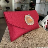 Sobre de fiesta rojo oscuro, tejido artesanalmente en la India, con cierre de solapa y broche magnético. Presenta un ágata central con borde dorado. Incluye asa de cadena dorada para llevar al hombro.