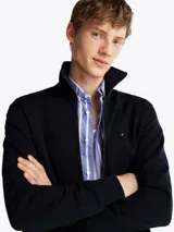Buzo azul marino de felpa de algodón con cuello chimenea, cierre de cremallera, dos bolsillos delanteros estilo canguro, puños y bajo de punto canalé, logo de Tommy Hilfiger bordado en el pecho y detalles distintivos de la marca.