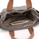 Bolso de lona color marrón con múltiples bolsillos externos frontales y laterales. Posee asas de mano y una correa larga ajustable y extraíble.