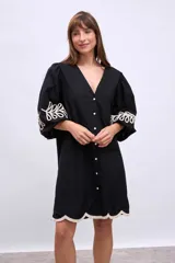 Vestido blanco de lino con escote en V, mangas cortas abullonadas y bordados florales en beige en mangas y ruedo.