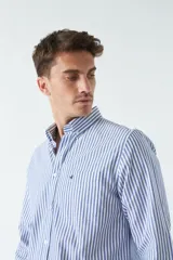 Camisa oxford a rayas verticales azules y blancas, de manga larga, con cuello abotonado, bolsillo en el pecho y logo bordado.