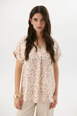 Blusa estampada con hojas azules sobre fondo blanco, con cuello en V y mangas cortas con dobladillo.