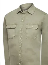 Camisa de denim color verde oliva, de manga larga, con dos bolsillos con tapeta y botones de madera en el pecho. Confeccionada con tecnología Natural Flex.