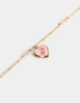 Collar corto dorado de doble cadena, con dije de relicario en forma de corazón con flores rosadas.