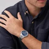Reloj Fossil plateado con esfera azul y tres subesferas. La correa es de acero plateado con cierre de hebilla desplegable.