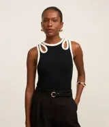 Blusa sin mangas confeccionada en rib de viscosa y elastano, color negro con ribete blanco. Posee breteles anchos con aberturas cutout en formato gotas y cuello redondo.