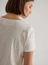 Remera gris de algodón y spandex, de manga corta y cuello redondo. Presenta líneas verticales en blanco y negro. Corte recto.