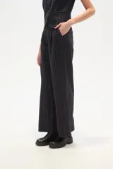 Pantalón de poliéster negro con rayas verticales blancas, de corte recto y tiro alto.