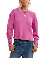 Buzo blanco de algodón con escote a la base, hombros caídos y mangas amplias con detalle de ojalillos y cordones en los puños.