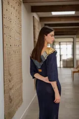 Vestido largo azul con cuello con apliques de cuero y flecos en el ruedo.