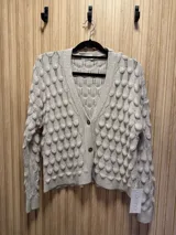 Saco de punto color gris claro con diseño de gotas en relieve, cuello en V y cierre con un botón.