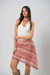 Minifalda roja con estampado de ondas en tonos rosados y beige, con corte irregular y cinturón marrón.