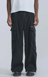 Pantalón técnico negro de silueta oversize, con cintura elástica, bolsillos cargo laterales y un cinturón de cinta con hebilla de plástico.
