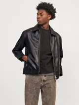 Chaqueta de cuero negra con cierre frontal con cremallera, cuello camisero, mangas largas con puños abotonados y bolsillos laterales con cierre.