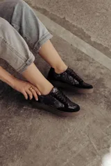 Zapatillas bajas color beige con estampado de piel de serpiente metalizada, cordones blancos y suela color caramelo.