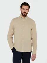 Camisa de vestir color beige claro, de corte clásico, con cuello abotonado y mangas largas.
