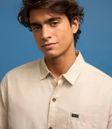 Camisa de hombre de corte relajado, color crudo, con cuello inglés, mangas cortas, abotonado delantero, bolsillo en el pecho y etiqueta de la marca.