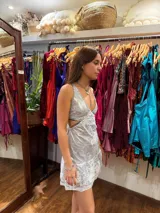 Vestido corto de lentejuelas color verde oliva, con escote en V, breteles finos cruzados en la espalda, cut-outs laterales y volado en el ruedo.