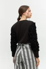 Remera negra de punto con mangas largas abullonadas con volantes.