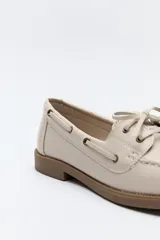Zapato náutico color beige, de símil cuero, con cordones y suela marrón antideslizante.