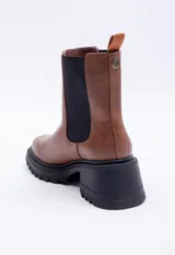 Bota de caña media con punta redondeada, en símil cuero negro, con piezas elastizadas en los laterales y plataforma de 6 cm.