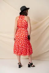 Vestido midi de gasa con seda, color rojo con lunares blancos, cuello halter, cintura elastizada con lazo y volado en el ruedo.