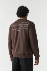 Buzo de felpa color gris claro, con cuello redondo, mangas largas y costuras a contratono. Presenta lettering estampado en el pecho, bolsillos laterales y logo en grifa de goma.