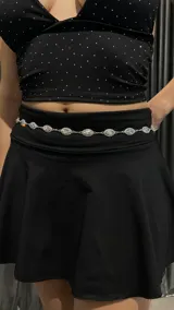 Cinturón plateado tipo caderín con cadena de eslabones y apliques de strass con forma de ojo.