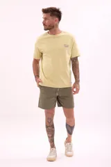Remera de manga corta color amarillo pálido con cuello redondo y un pequeño logo estampado en el pecho izquierdo.