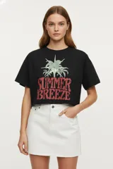 Remera negra de algodón con estampado de palmeras y texto 'Summer Breeze' en el frente, corte holgado y mangas cortas.