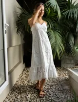 Vestido blanco de broderie con escote en V, corte bajo el busto y breteles finos cruzados en la espalda. Tiene forro interno a tono y largo midi.