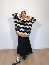 Sweater tejido a mano con lana merino, con diseño de ondas en colores beige, negro, blanco y azul.