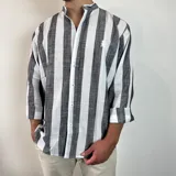 Camisa celeste y blanca a rayas verticales, de lino, con cuello mao y mangas largas con puños.