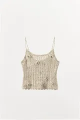 Top de crochet color beige, con tirantes finos y escote redondo. Presenta apliques de flores en relieve y abalorios plateados.