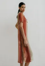 Vestido midi de red con estampa degradé en tonos naranja, beige y verde. Tiene tajos a los costados.