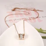 Collar con cadena fina color oro rosa y dije cilíndrico con centro de circonitas blancas y bordes lisos color oro rosa.