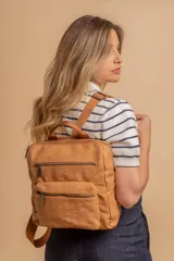 Mochila mediana de símil cuero color beige, con asa superior, dos compartimentos principales con cierre y dos bolsillos frontales con cierre. Las correas son ajustables y de color beige.