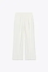 Pantalón blanco de tiro alto con pinzas, bolsillos delanteros y falsos bolsillos de vivo en la espalda. Tiene pernera ancha y cierre frontal con cremallera, botón interior y gancho.